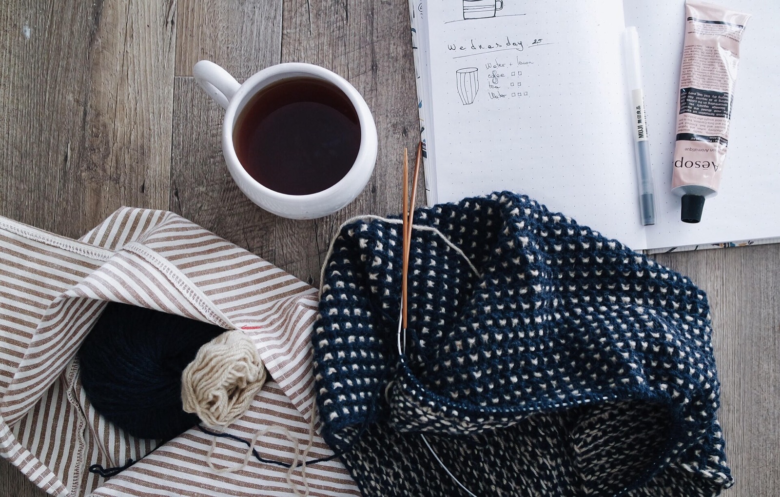 Knitting, a notebook and a cup of coffee on a café table